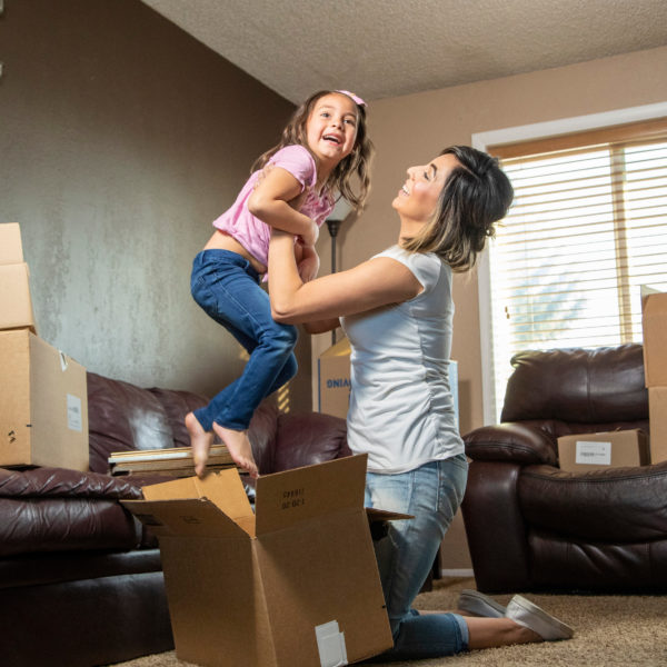 A Hispanic mother holds daughter up in a new House