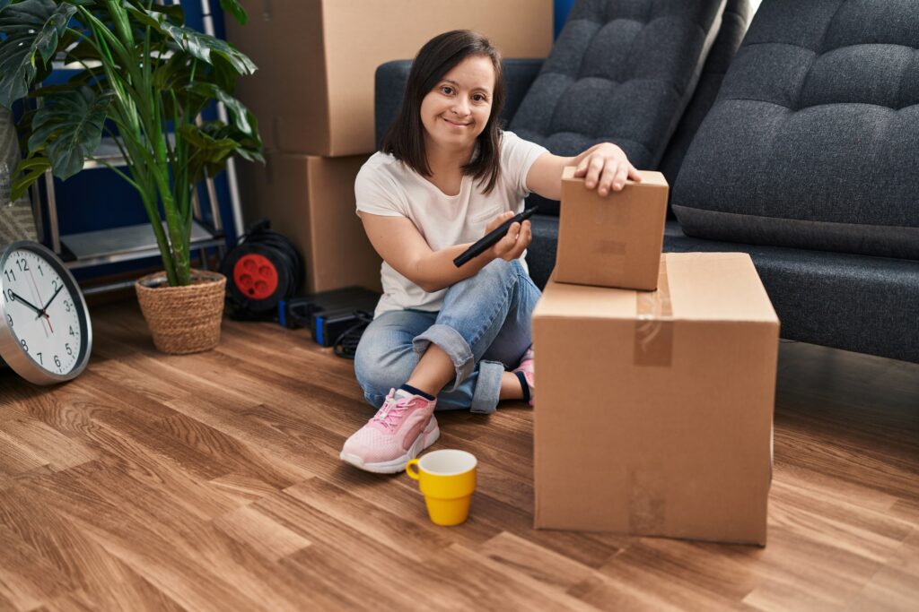 Down syndrome woman smiling confident writing on package at new home