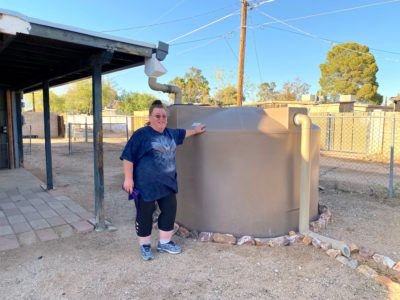 Lora with her rainwater harvesting tank