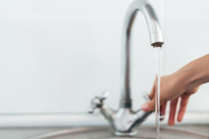 woman hand opening silver faucet or water tap with metal washing