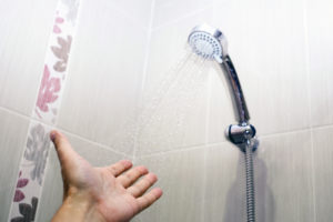 Close-up of a man hand check water temperature in the shower with hand shower wall. selective focus