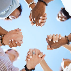 Diversity, support and people holding hands in trust and unity for community against sky background. Hand of diverse group in solidarity for united team building collaboration and teamwork success